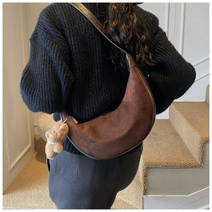 Retro brown suede crescent bag detail featuring a cute plush bear pendant and strap