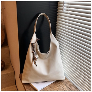 Detail view of large beige hobo tote bag with a colorful ethnic tassel and charm