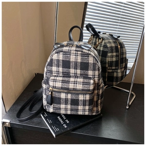Detail of black and white plaid tweed texture and leather handles on vintage backpack
