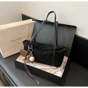 Detail of black tote bag inside a luxury gift box with a baseball charm and silk lining