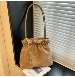 Detail of khaki faux suede bucket bag featuring drawstring pleats and thin strap