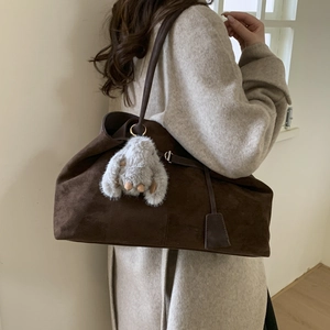 Close-up of large matte brown tote bag with fuzzy charm and soft texture detail