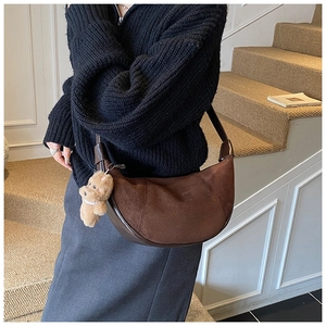 Detail of dark brown suede hobo bag with leather strap and cute bear charm pendant
