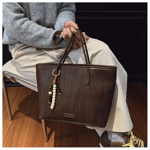 Detailed weave texture of dark brown tote bag with ethnic beaded charm and brand logo