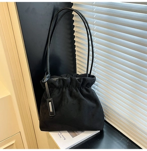 Detail shot of black faux suede bucket bag with drawstring closure and silver metal hardware