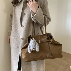 Detail shot of brown frosted tote bag showing soft suede texture and plush rabbit charm