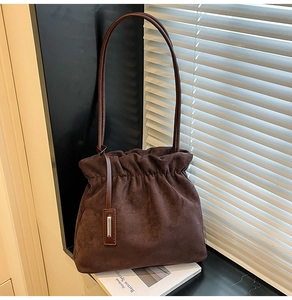 Close-up of deep brown suede bucket bag featuring drawstring pleats and silver metal hardware