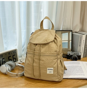 Détail d'un sac à dos en nylon kaki avec fermeture à cordon et poche zippée avant