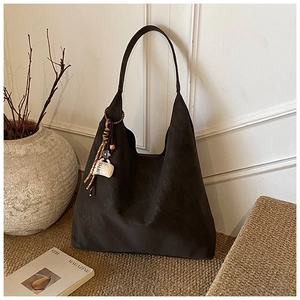 Detailed shot of coffee charm and suede tassel on a dark hobo tote bag for daily commute
