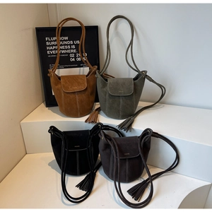Détail de sacs seaux mats en marron et vert avec pompons et texte de mode élégant