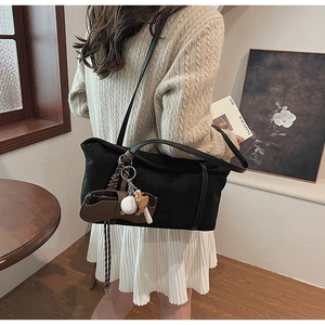 Close-up of black fabric tote bag featuring a mini saddle pouch and baseball charm