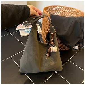 Detail view of large olive green suede tote bag with fringe and coffee cup pendant charm