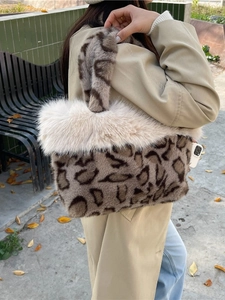 Faux fur leopard print handbag with plush cream trim shown in an outdoor autumn setting