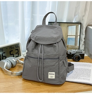 Détail macro d'un sac à dos gris en nylon avec rabat à cordon et poches latérales élastiques