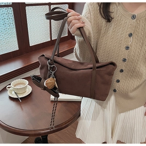 Detailed view of deep brown suede handbag with slim handle on a vintage cafe table