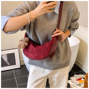 Detail of burgundy crossbody bag with suede finish and cute brown bear keychain