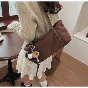 Detailed view of deep brown suede hobo bag with unique baseball leather charm