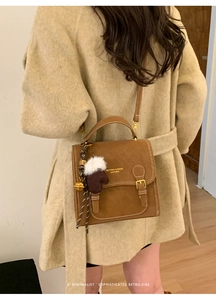 Detailaufnahme der braunen Retro-Ledertasche mit weißen Nähten und Plüschhandschuh-Anhänger