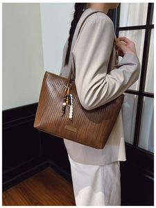 Detail shot of brown woven leather tote bag with wooden beads and brand logo