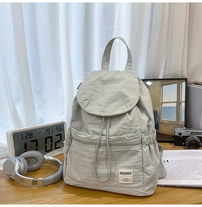 Détail d'un sac à dos en nylon gris clair avec texture froissée et fermeture à cordon