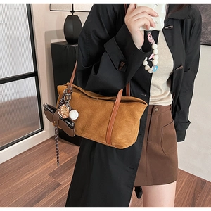 Detail of a brown suede tote bag with unique baseball and mini pouch charms