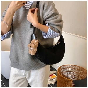 Chic black half-moon crossbody bag with cute teddy bear charm on casual female model