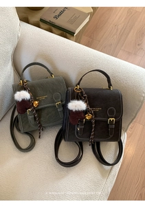 Nahaufnahme von Vintage-Rucksäcken mit Goldlogo und Glockenanhänger auf dem Sofa