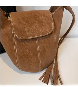 Détail du sac marron texture litchi avec surpiqûres blanches et marquage doré