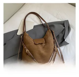 Détail d'un sac cabas en daim marron avec boucle en cuir et logo doré élégant