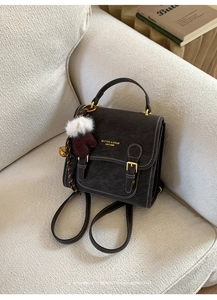 Detailansicht eines Vintage-Lederrucksacks mit goldenen Beschlägen und weichem Anhänger