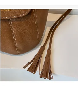 Détail du sac en cuir marron avec surpiqûres blanches et cordon de serrage à glands