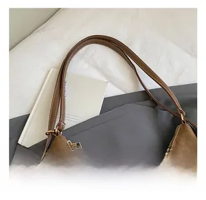 Détail d'un sac à bandoulière en daim marron avec sangle réglable et boucle en métal