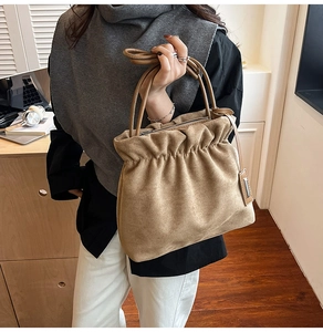 Brown pleated bucket bag in suede with cloud-like texture and metallic pendant detail