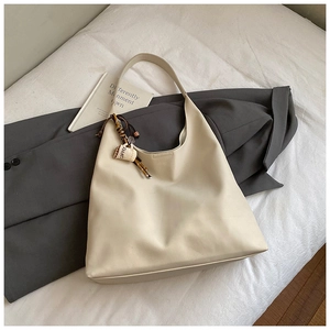 Detail of cream-colored hobo tote bag featuring a cute coffee cup charm on the shoulder strap