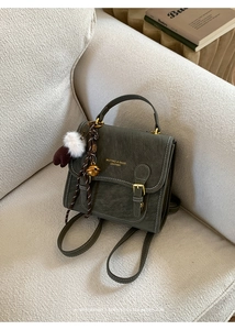 Details des olivgrünen Vintage-Lederrucksacks mit Goldbeschlägen und Plüsch-Anhänger