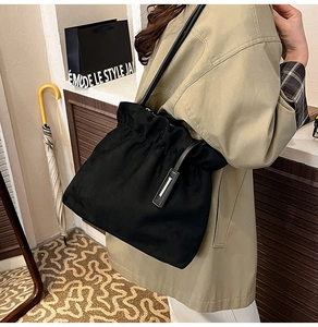 Detail of black drawstring pleated bucket bag showing matte texture and slouchy drape