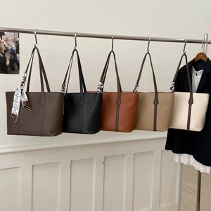 Detail view of various minimalist tote bags in five colors with slim straps and silk scarf
