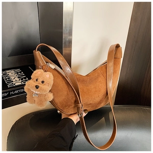 Detail view of brown patchwork crescent bag with adjustable strap and plush dog charm