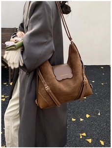 Détail du grand sac cabas en daim marron avec anses en cuir et boucles argentées de luxe
