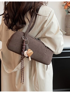 Retro dark brown hobo shoulder bag with unique mushroom charm on a beige trench coat