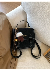 Details des schwarzen Vintage-Mini-Rucksacks mit Kontrastnähten und Anhängern