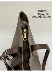 Detail of premium brown tote bag featuring smooth gold zipper and silk scarf handle decor
