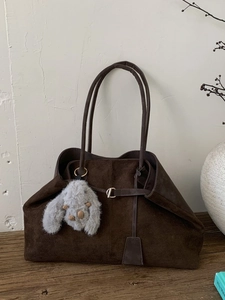Large dark coffee frosted tote bag with plush rabbit charm on a vintage wood stand