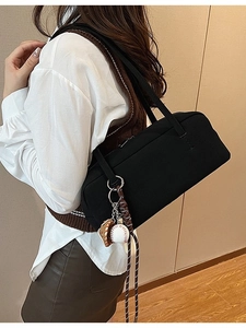 Minimalist black boston shoulder bag with baseball charms shown on model in studio