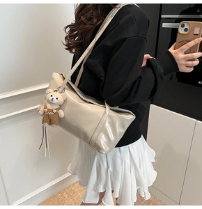 Borsa tote beige in ecopelle con ciondolo a forma di orso indossata da una modella