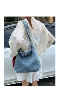Detail shot of a large denim bucket bag featuring Leisurely Carefree printed text on shoulder