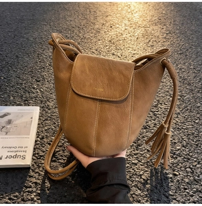 Détails du sac seau vintage marron avec surpiqûres blanches et pompon au coucher du soleil