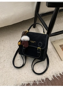 Detail eines schwarzen Vintage-Rucksacks mit weißen Nähten und Plüsch-Anhänger