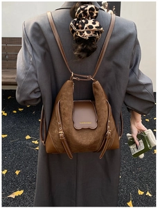 Détail d'un sac à bandoulière en daim marron porté par un mannequin en blazer gris