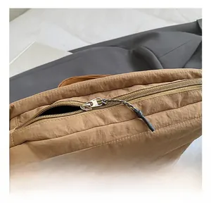 Close-up of the metal zipper and woven puller on the khaki nylon quilted shoulder bag